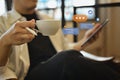 Young man holding coffee cup and using digital tablet with icons social media notifications Royalty Free Stock Photo