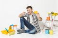 Young man holding credit card with money sitting on floor with instruments for renovation apartment isolated on white Royalty Free Stock Photo