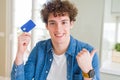 Young man holding credit card pointing and showing with thumb up to the side with happy face smiling Royalty Free Stock Photo