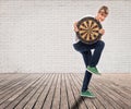 Young man holding a dartboard on a room