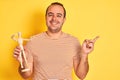 Young man holding figure of art dummy standing over isolated yellow background very happy pointing with hand and finger to the Royalty Free Stock Photo