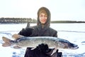 Young man holding fish catch a big pike ice fishing Royalty Free Stock Photo