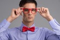 Young man holding glasses on grey background. Royalty Free Stock Photo