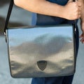 Young man holding a gray shiny messenger sport bag