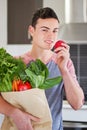 Young man holding groceries eating an apple Royalty Free Stock Photo