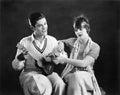 Young man holding a guitar with a young woman teaching him how to play