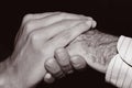 Young man holding the hand of an old man, in black and white