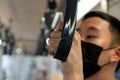 Young man holding a handrails in metro subway train while wearing black surgical mask in public transportation for