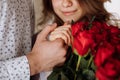 young man holding his fiance's hand with gold ring while making a marriage proposal with bouquet of red roses Royalty Free Stock Photo