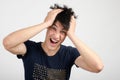 Young man holding his head frowning with worry screaming. Royalty Free Stock Photo