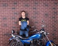 Young Man Holding his Jacket Behind his Motorcycle Royalty Free Stock Photo