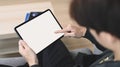 Young man holding horizontal digital tablet with blank screen while sitting on couch.