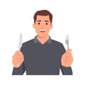 Young man holding knife and fork. Hungry man waiting for food.