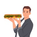 Young man holding a long sandwich with a fresh salad
