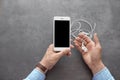 Man holding mobile phone with blank screen and earphones in hands over table Royalty Free Stock Photo