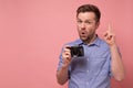 Young man holding photocamera taking photo pointing with index finger up giving advice