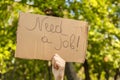 Young man holding piece of cardboard with text NEED JOB outdoors Royalty Free Stock Photo