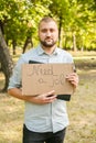 Young man holding piece of cardboard with text NEED JOB outdoors Royalty Free Stock Photo