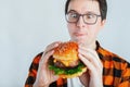 Young man holding a piece of hamburger. Student eats fast food. Burger is not helpful food. Very hungry guy looks at the burger an Royalty Free Stock Photo
