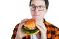 Young man holding a piece of hamburger. Student eats fast food. Burger is not helpful food. Very hungry guy looks at the burger Royalty Free Stock Photo