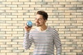 Young man holding piggy bank on brick background. Savings money concept Royalty Free Stock Photo