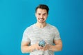 Young man holding piggy bank on color background. Savings money concept Royalty Free Stock Photo