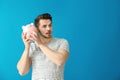 Young man holding piggy bank on color background. Savings money concept Royalty Free Stock Photo