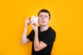 Young man holding at piggy bank and looking suspiciously Royalty Free Stock Photo