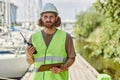 Young man holding radio and looking at camera working in yacht docks