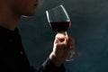 Young man holding red wine glass against dark background Royalty Free Stock Photo