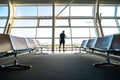 Rear view. Young man holding smartphone in hands while standing in airport terminal Royalty Free Stock Photo