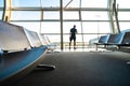 Young man holding smartphone in hands while standing in airport terminal. Focus on bench Royalty Free Stock Photo