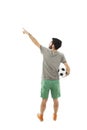 Young man holding soccer ball, pointing. Rear view