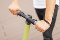 Young man is holding the steering wheel of an electric scooter. Guy with a modern scooter. Close-up male hands and steering wheel.