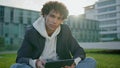 Young man holding tablet at grass portrait. Curly youngster looking camera