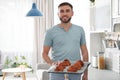 Young man holding tray of freshly oven baked buns