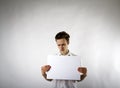 Young man holding white paper in his hands. Unhappy. Royalty Free Stock Photo