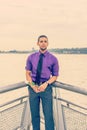 Young man holding white rose,  standing outdoors by river in New York City, looking forward Royalty Free Stock Photo