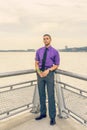 Young man holding white rose,  standing outdoors by river in New York City, looking forward Royalty Free Stock Photo