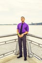 Young man holding white rose,  standing outdoors by river in New York City, looking forward Royalty Free Stock Photo