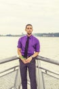 Young man holding white rose,  standing outdoors by river in New York City, looking forward Royalty Free Stock Photo