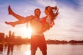 Young man holding woman on summer river bank. Couple having fun at sunset. Guys chilling Royalty Free Stock Photo