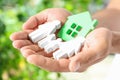 Young man holding wooden family figure and house model in his hands against blurred background Royalty Free Stock Photo