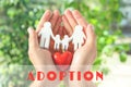 Young man holding wooden family figure and red heart in his hands against blurred background. Child adoption concept Royalty Free Stock Photo