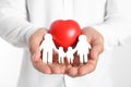 Young man holding wooden  figure and red heart on white background, closeup of hands Royalty Free Stock Photo