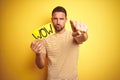 Young man holding wow text banner over yellow isolated background pointing with finger to the camera and to you, hand sign, Royalty Free Stock Photo