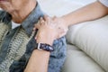 Young man holding wrinkled hand of his father