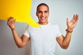 Young man holding yellow speech bubble over white isolated background very happy and excited, winner expression celebrating Royalty Free Stock Photo