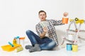 Young man holds bundle of dollars, cash money, sits on floor with paint can, instruments for renovation apartment Royalty Free Stock Photo
