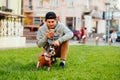 Young man holds a dog on a leash and uses a smartphone on the lawn on the street. Guy walks the dog and uses the Internet